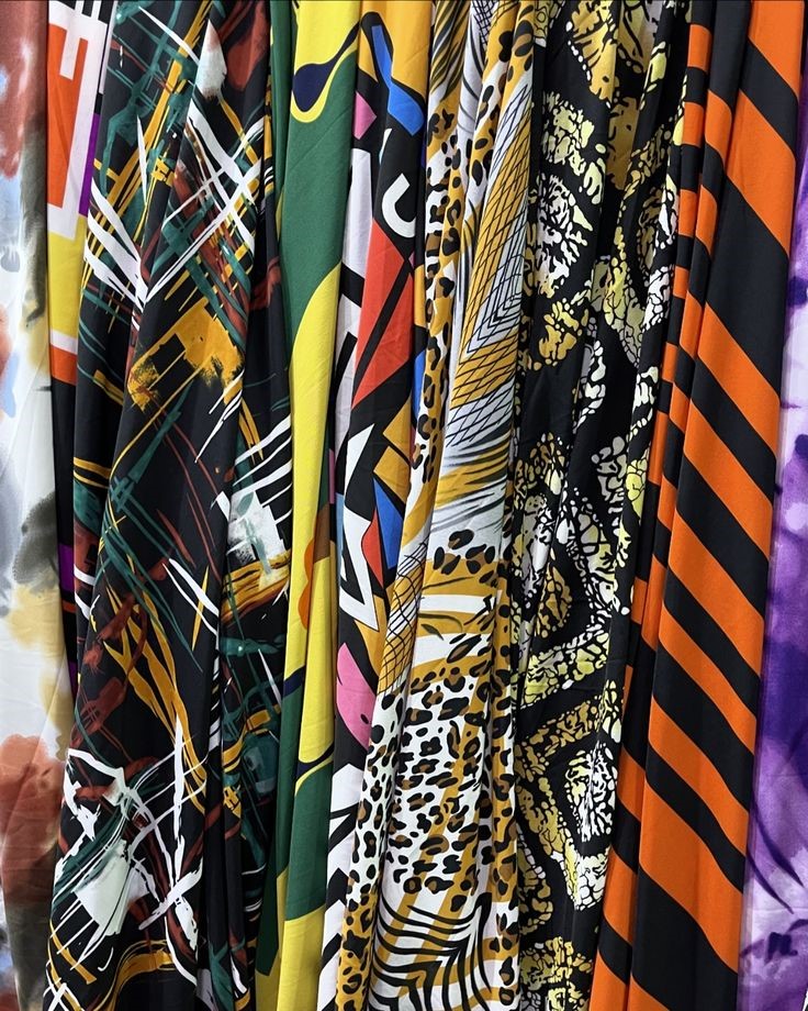 Collection of colorful printed fabrics featuring floral, geometric, striped, and animal print patterns for fashion design.