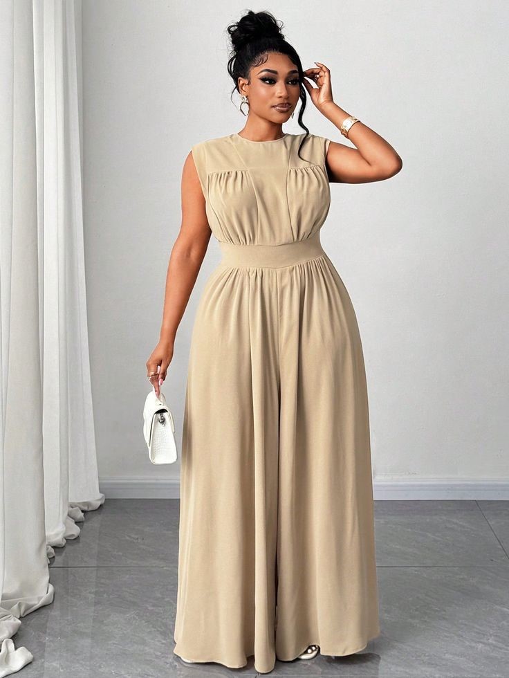 Plus-size woman wearing a cream and beige sleeveless jumpsuit styled with a white handbag to showcase how soft neutral colors create an elegant, flattering look.
