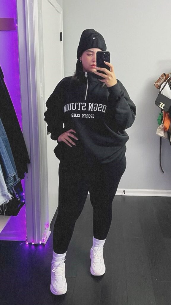Plus-size woman wearing a hoodie with straight-leg joggers and classic trainers.