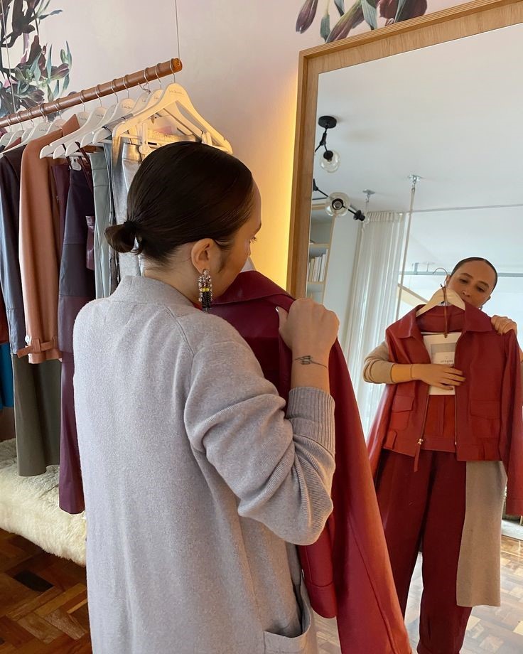 Woman selecting a tailored jacket in an elegant boutique while building a timeless luxury wardrobe.