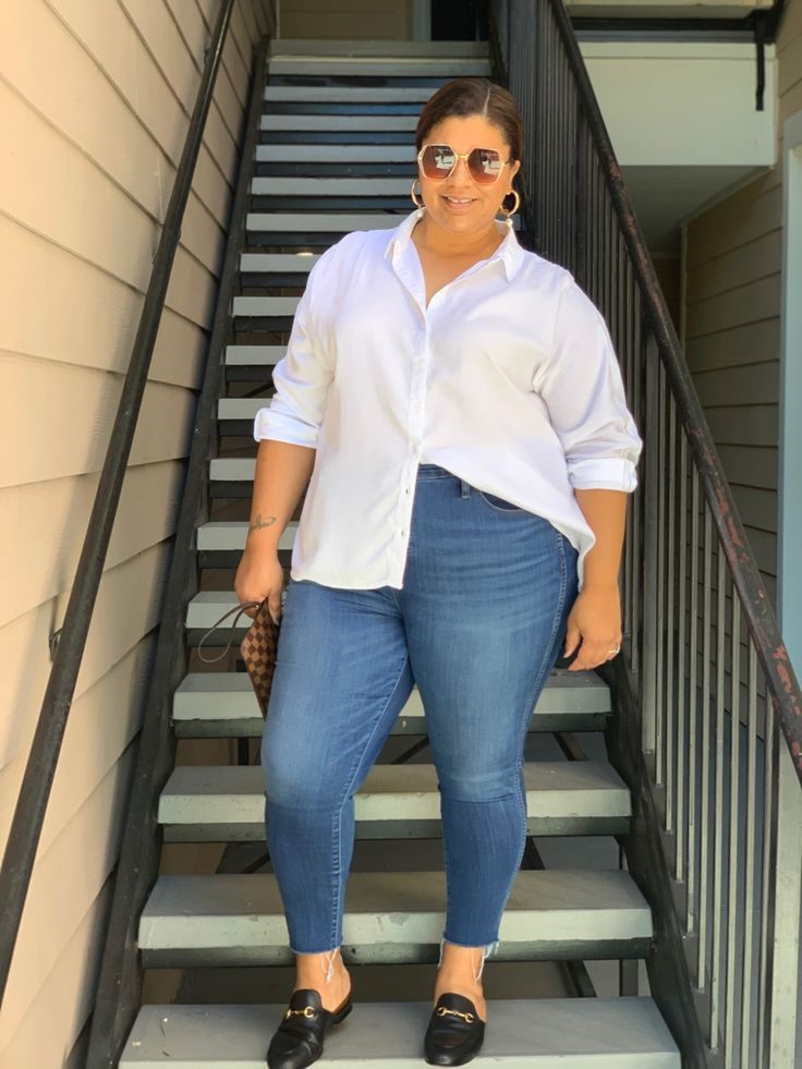 Plus-size woman wearing an oversized button-up shirt with dark-wash jeans