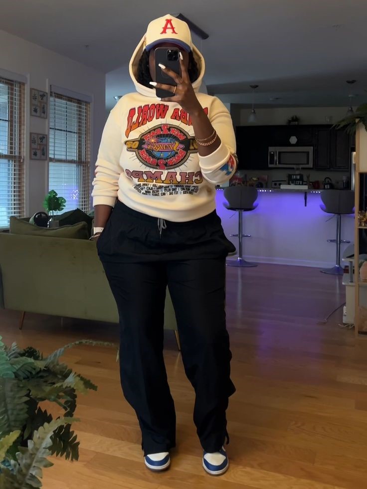 Plus-size woman wearing a graphic sweatshirt with black joggers and sneakers for a casual rainy-day outfit.