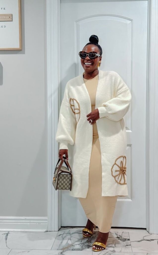 Plus-size woman wearing a beige midi dress with a long cream cardigan for a chic rainy-day outfit.