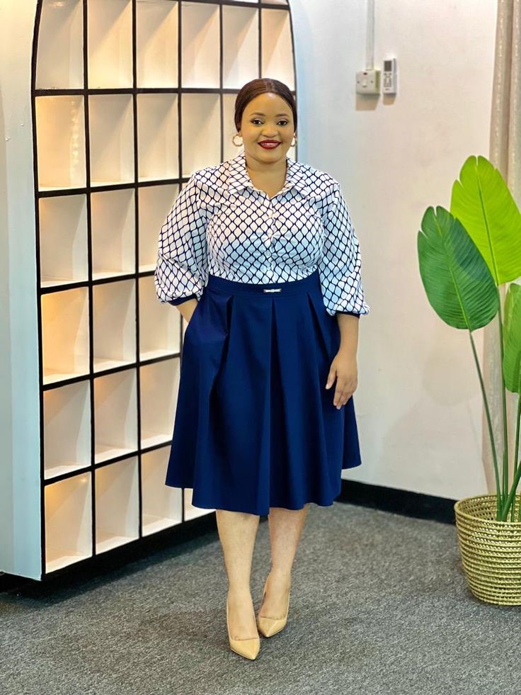 Plus-size woman wearing a printed button-down blouse with a navy A-line midi skirt for a comfortable office outfit.