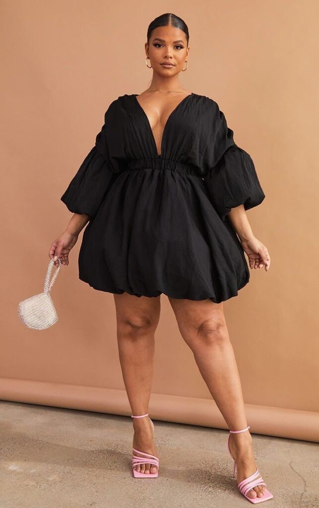 Plus size woman wearing a stylish puff sleeve little black dress.
