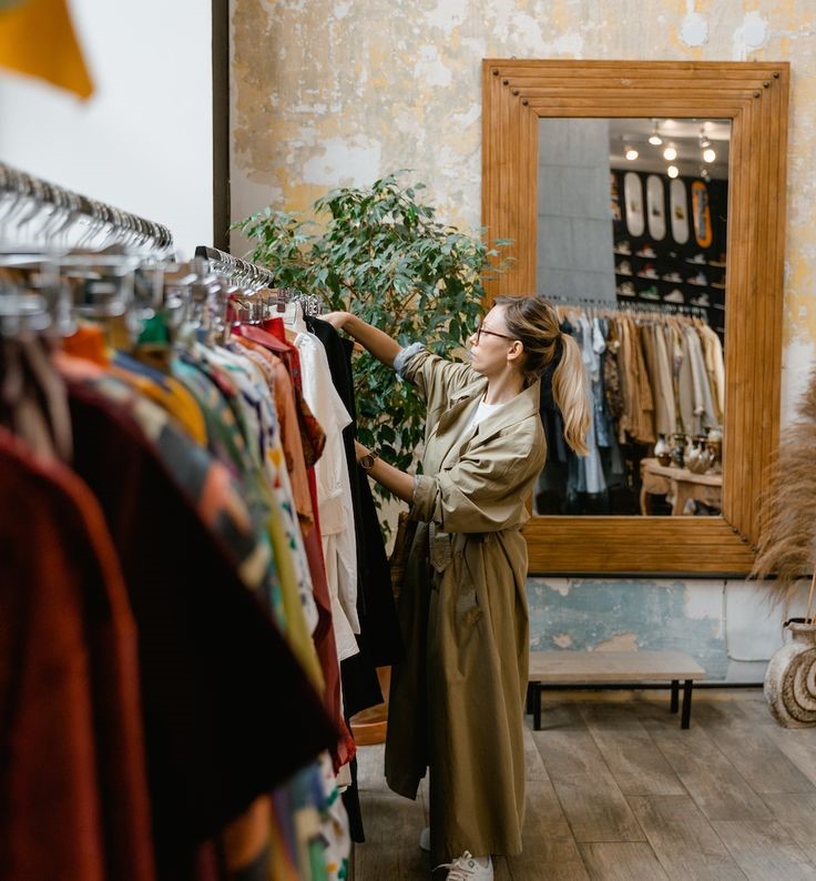 Woman browsing a clothing rack while choosing stylish wardrobe pieces in a boutique.