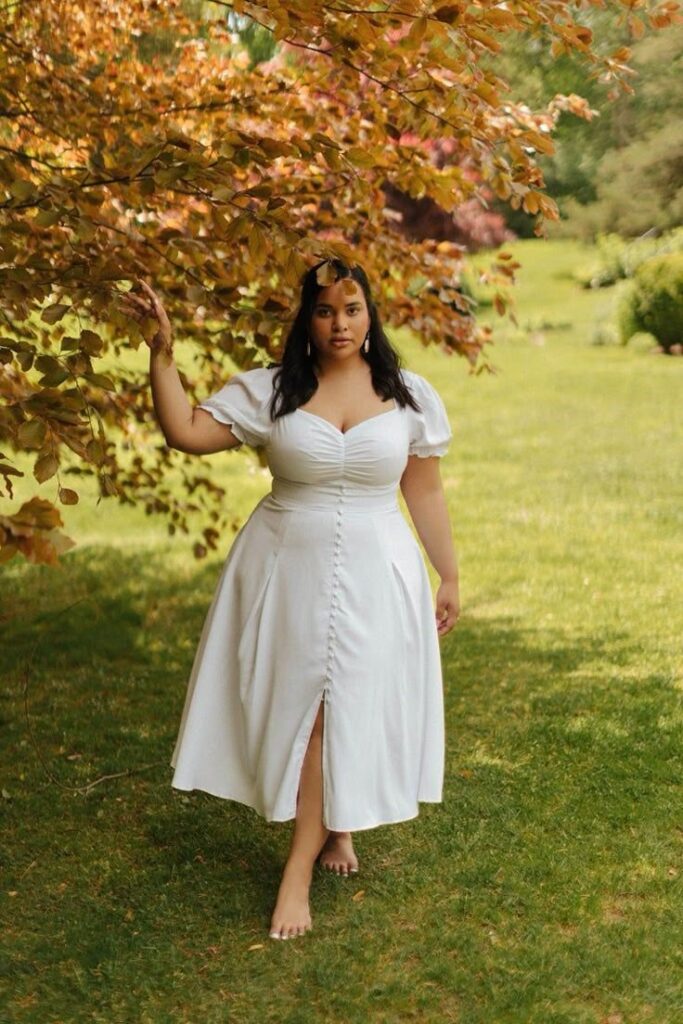 Curvy woman wearing a floral smocked midi dress at a garden picnic.