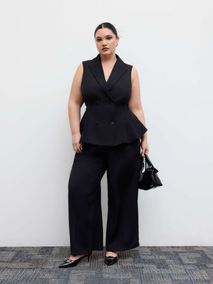 Plus size woman wearing a black tailored longline vest with matching wide-leg trousers and pointed-toe heels for a business casual office outfit.
