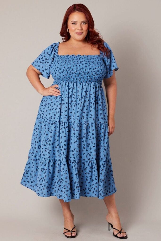 Curvy woman wearing a flowing tiered midi dress with layered details.