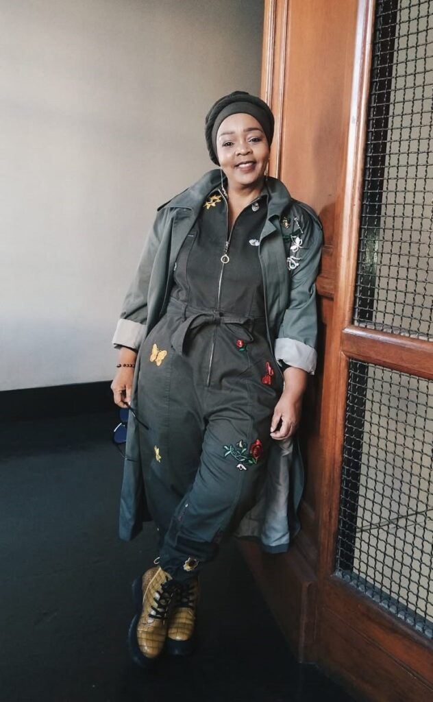 Plus-size woman wearing a utility jumpsuit with a lightweight waterproof jacket for a stylish rainy-day outfit.