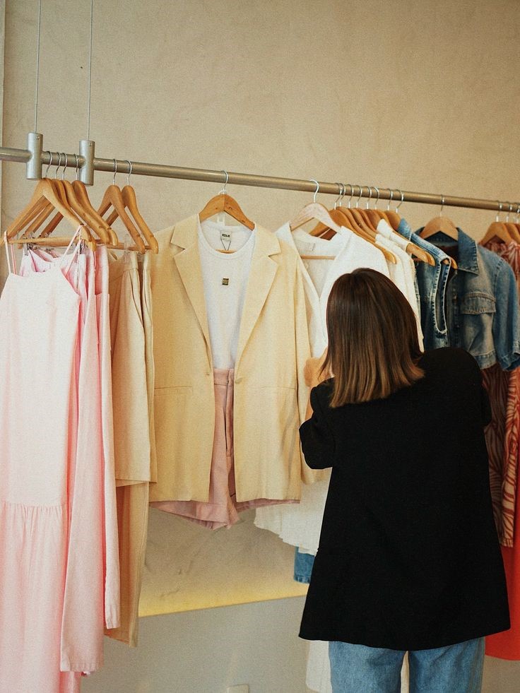 Woman thoughtfully choosing clothes from a clothing rack before shopping