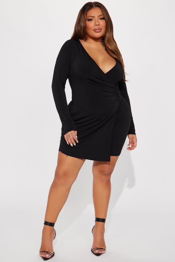 Plus size woman wearing a flattering wrap little black dress with nude heels.