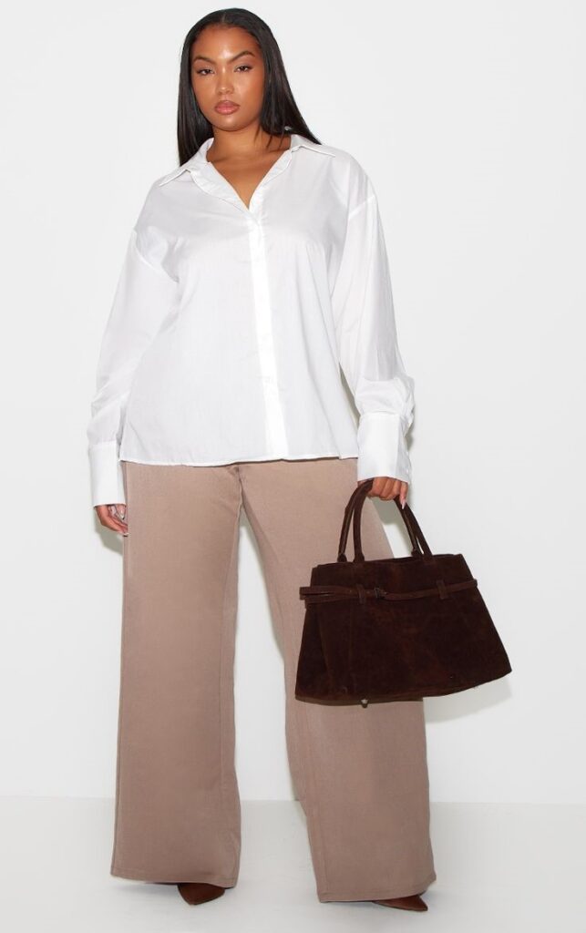Plus size woman wearing a white button-down shirt with tailored wide-leg trousers