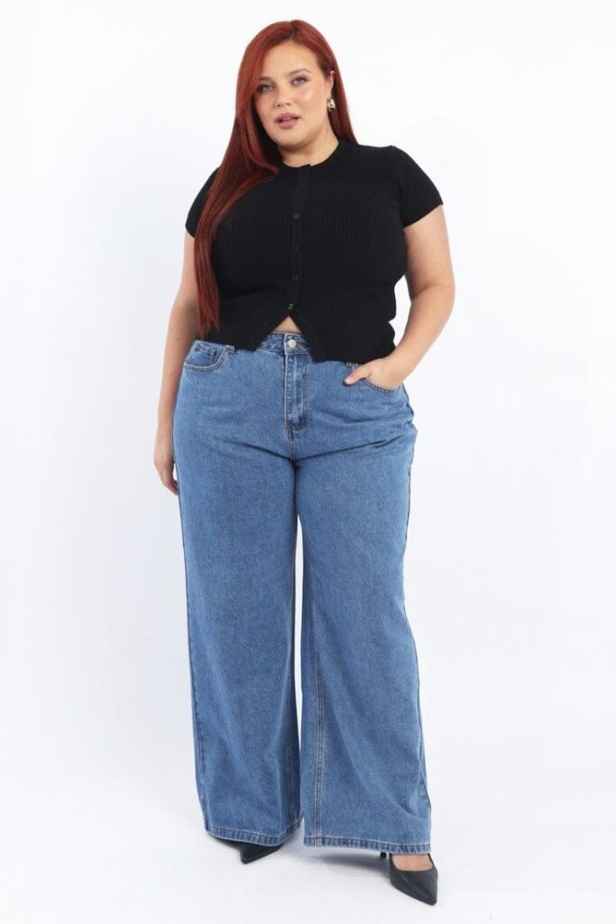 Plus size woman wearing a simple black knit top with wide-leg jeans