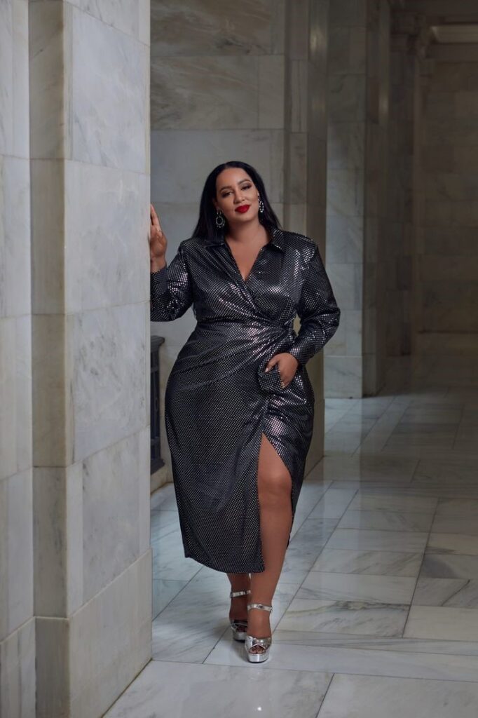 Apple-shaped plus-size woman wearing a metallic wrap midi dress with a flattering V-neck and draped silhouette.