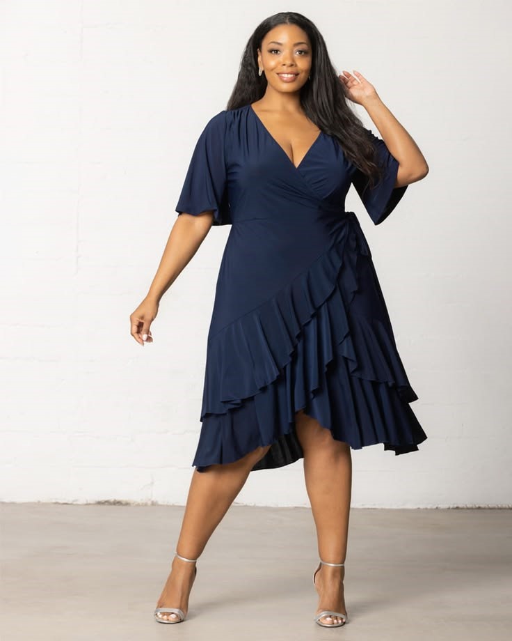 Plus-size woman wearing a navy wrap-style midi dress with soft draping and flutter sleeves.