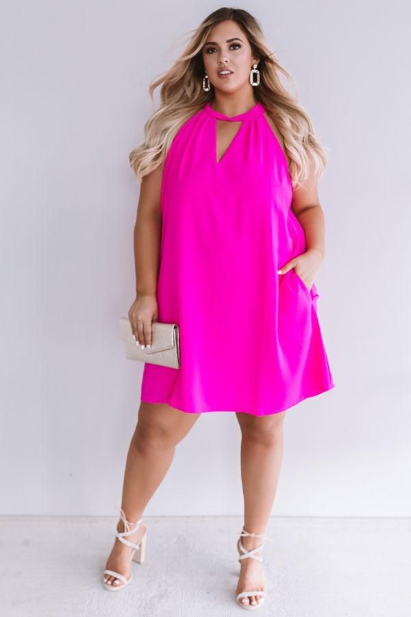 Apple-shaped plus-size woman wearing a bright pink shift dress with a flattering halter neckline.