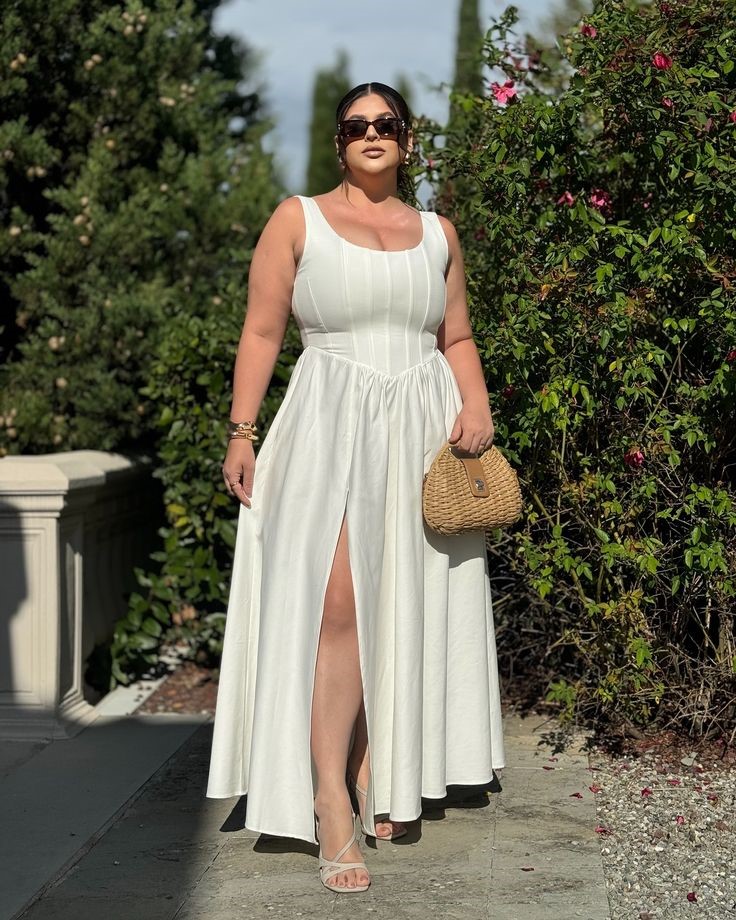 Apple-shaped plus-size woman wearing a white A-line maxi dress with a square neckline and flowing skirt.
