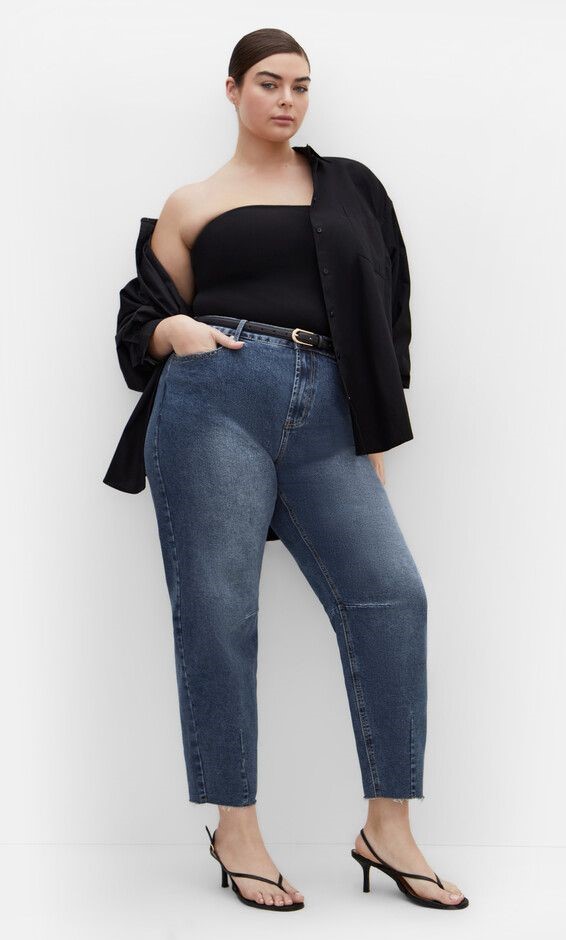 Woman wearing cropped blue jeans with a black top, blazer, and heeled sandals