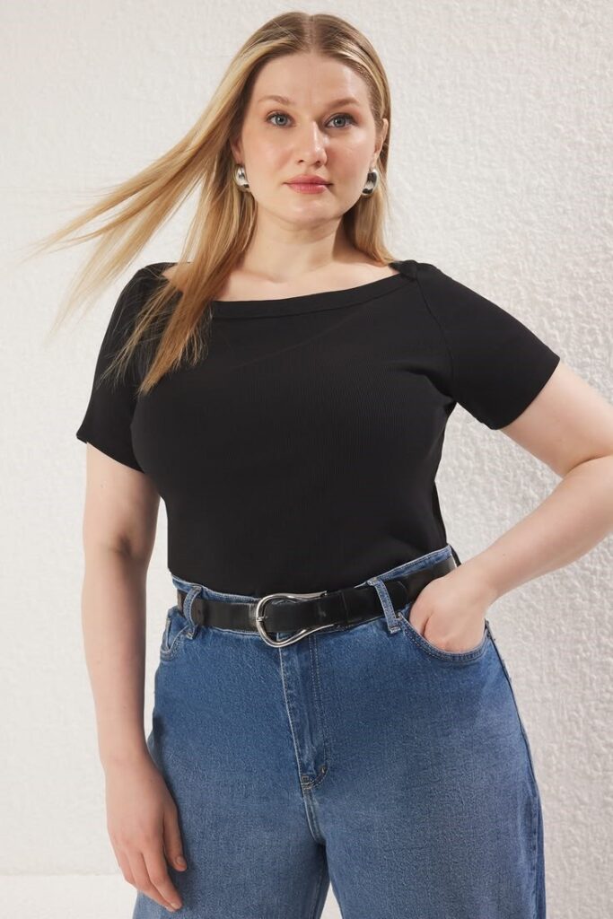 Best tops for a pear-shaped body, featuring a woman wearing a flattering black boat neck top.