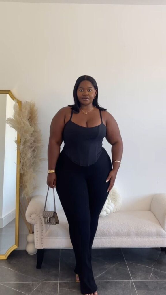 Hourglass plus size woman wearing a structured black top and high-waisted trousers that flatter her natural shape