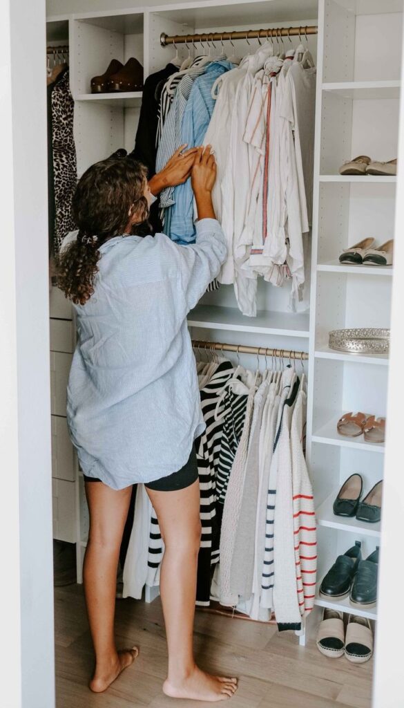 Woman choosing clothes from her wardrobe while learning how to build a closet she'll actually wear