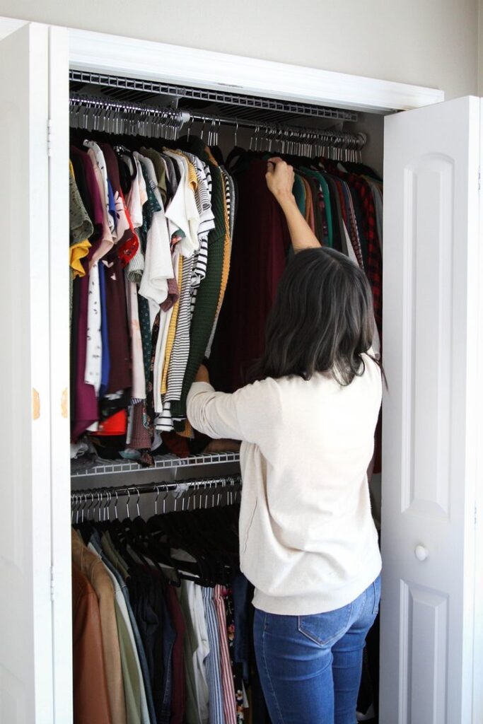 Woman looking through a full closet while considering what she'll actually wear