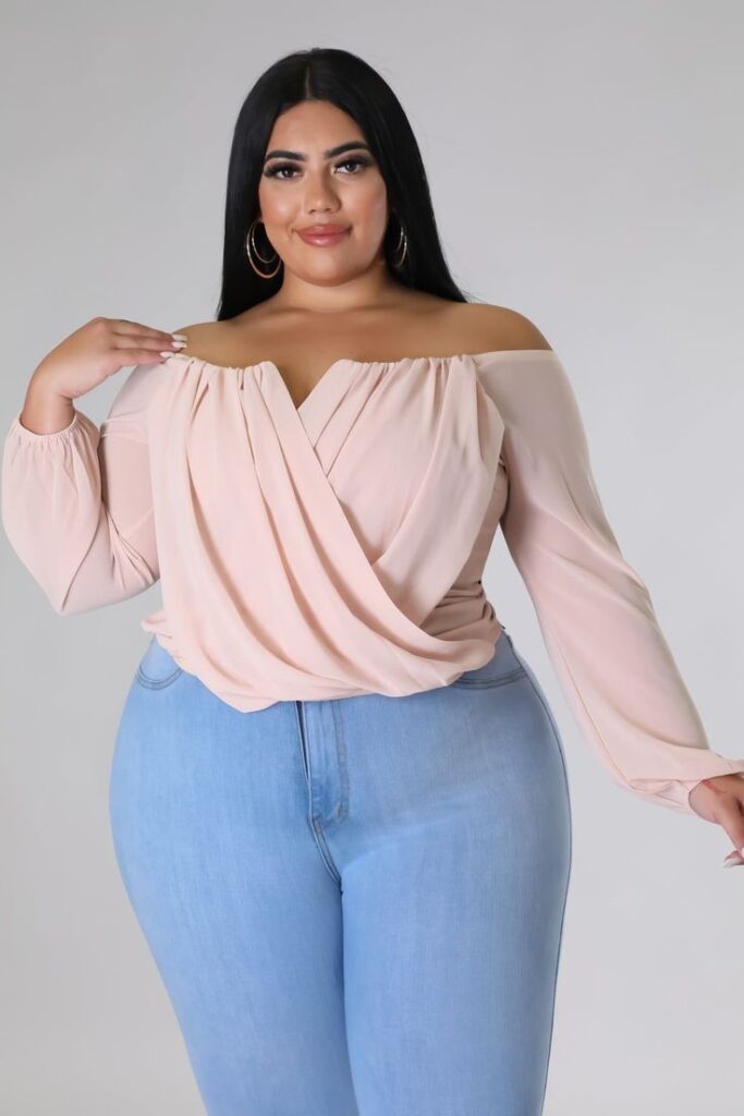 Curvy woman wearing light-wash jeans and a soft pink blouse, showing a stylish everyday look that avoids jeans mistakes that make outfits look frumpy