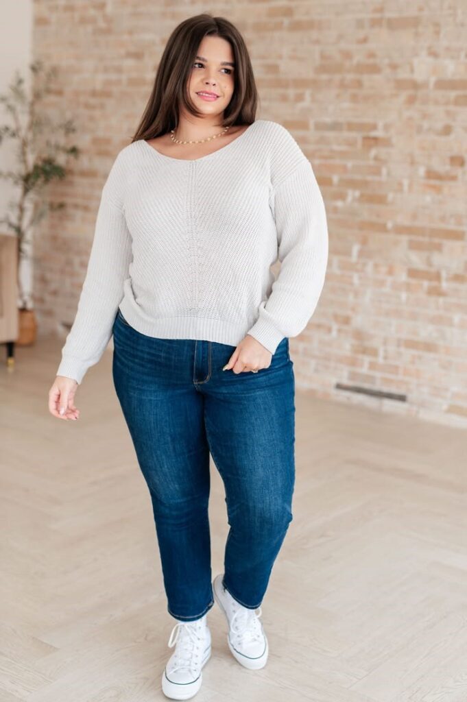 A woman wearing a lightweight knit sweater with jeans 