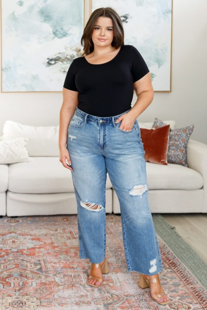 Pear-shaped plus-size woman wearing flattering straight-leg jeans and a fitted black top.