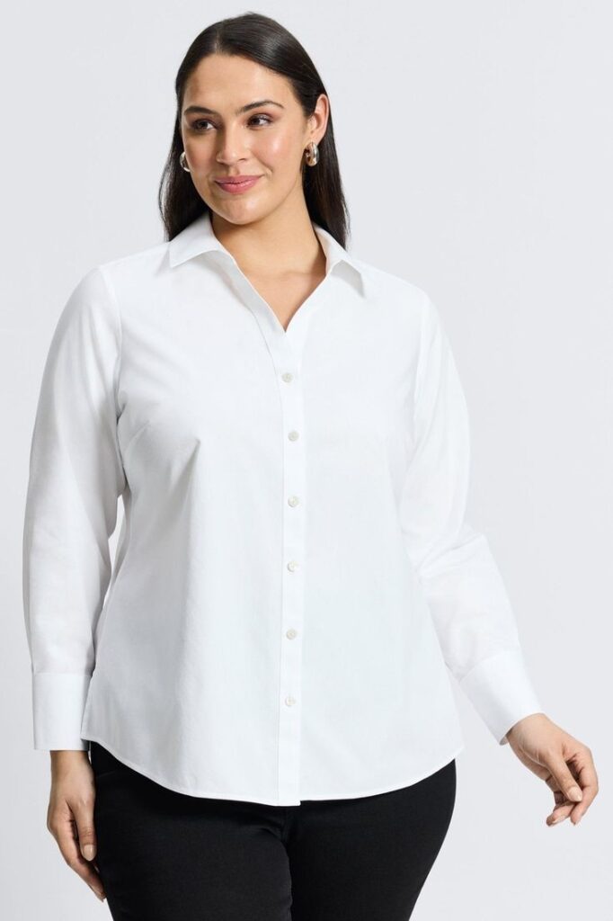Plus size woman wearing a classic white button-down shirt with black pants, styled as a versatile wardrobe essential for creating multiple outfits.