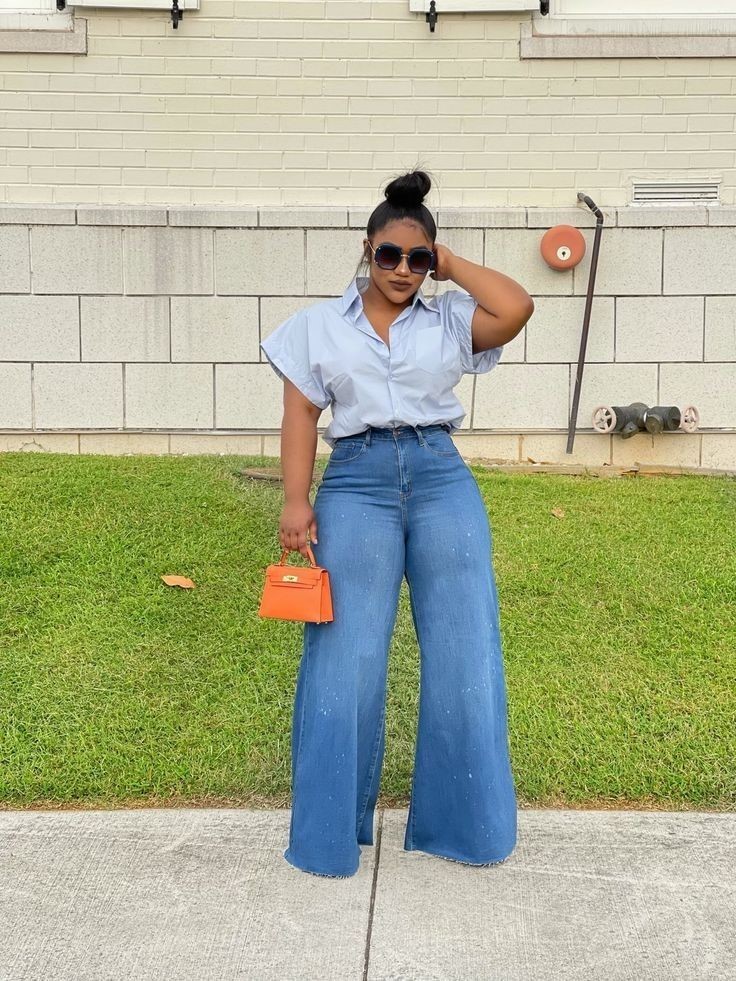 Curvy woman wearing wide-leg jeans with a tucked light blue button-down shirt