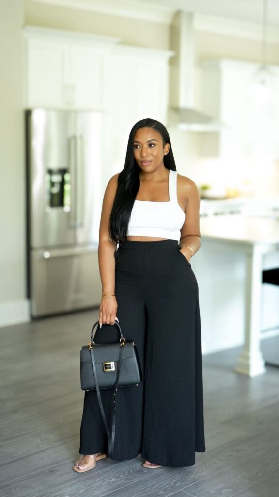 Woman wearing high-waisted black wide-leg trousers with a fitted white top