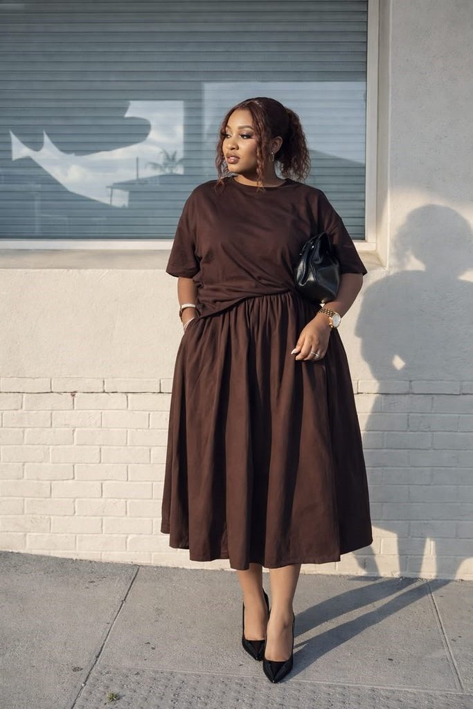 Plus size woman wearing a chocolate brown monochrome outfit with a midi skirt for a balanced silhouette