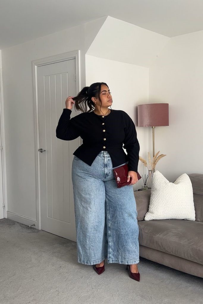Plus size woman wearing a fitted black top and wide-leg jeans to create a balanced silhouette