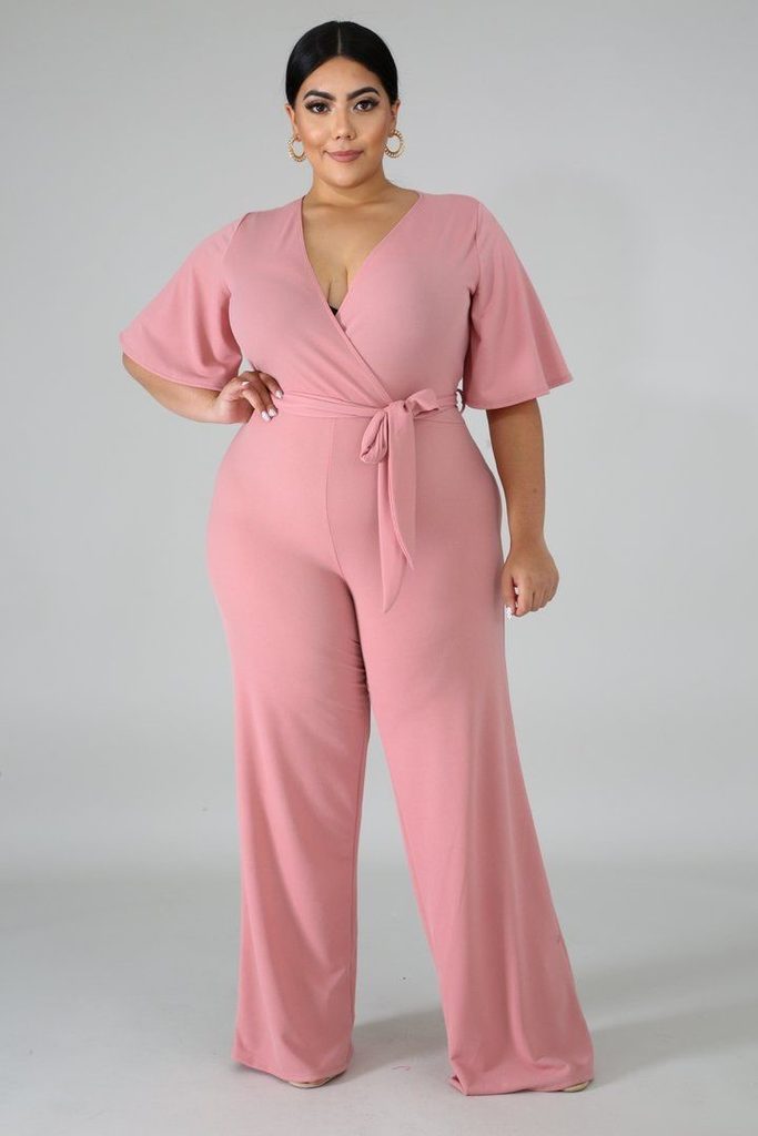Plus size woman wearing a blush pink wide-leg jumpsuit for a baby shower