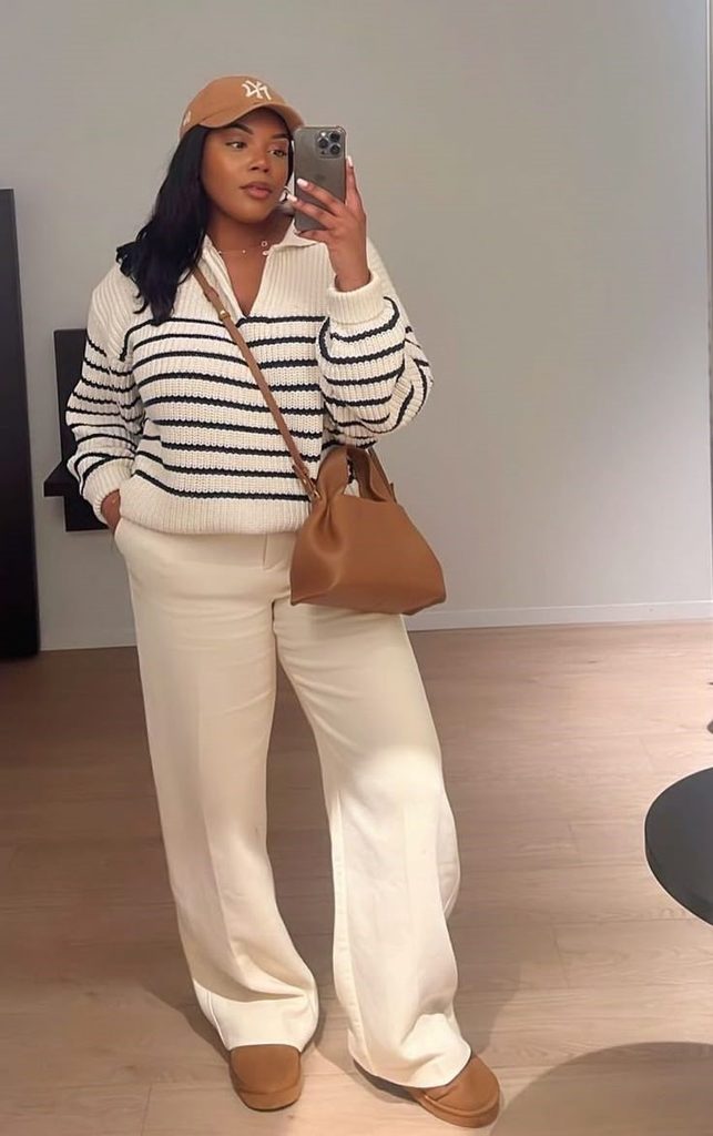 Plus size woman feeling beautiful in every outfit wearing a neutral striped sweater and wide leg trousers