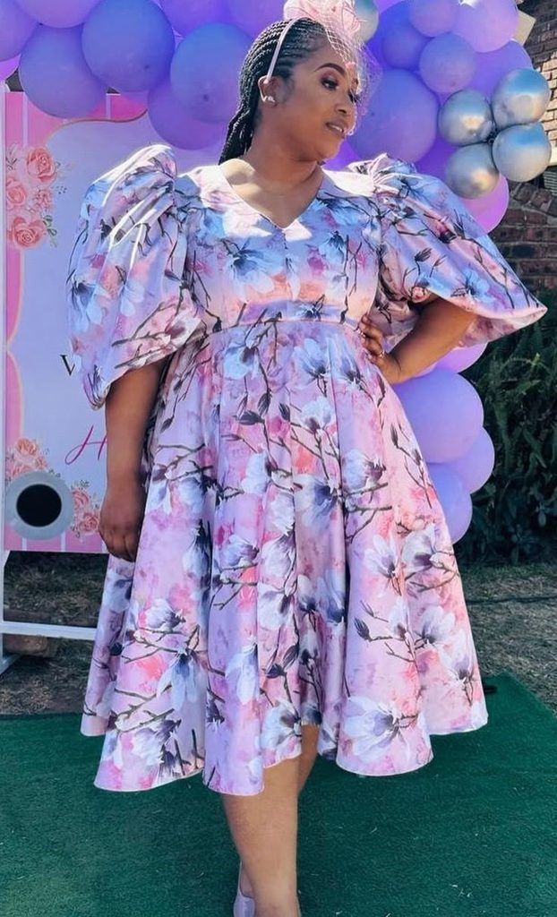 Plus size woman wearing a floral midi dress with puff sleeves for a baby shower