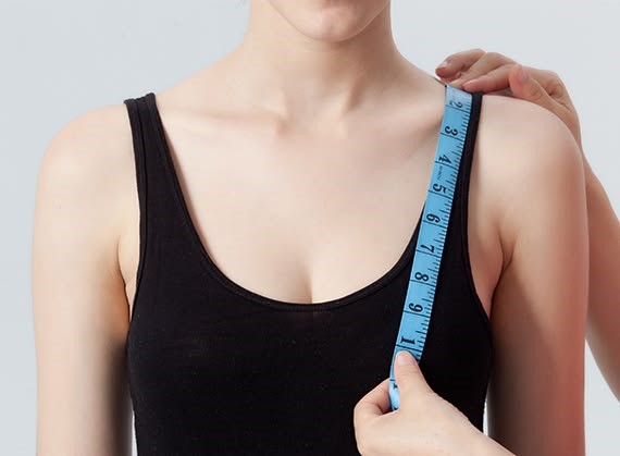 Woman measuring the fullest part of her bust to find a bra that actually fits