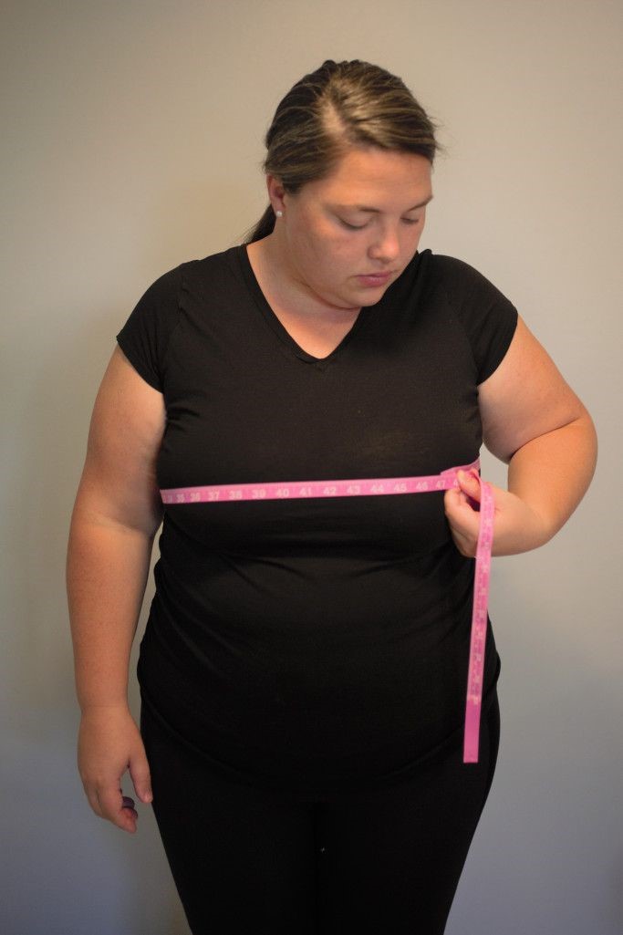 Plus size woman measuring her bust to find a bra that actually fits