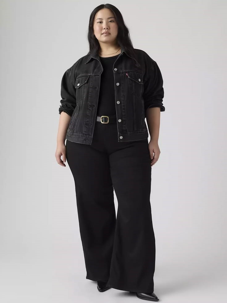 Plus size woman wearing black wide-leg jeans with a black top and black denim jacket