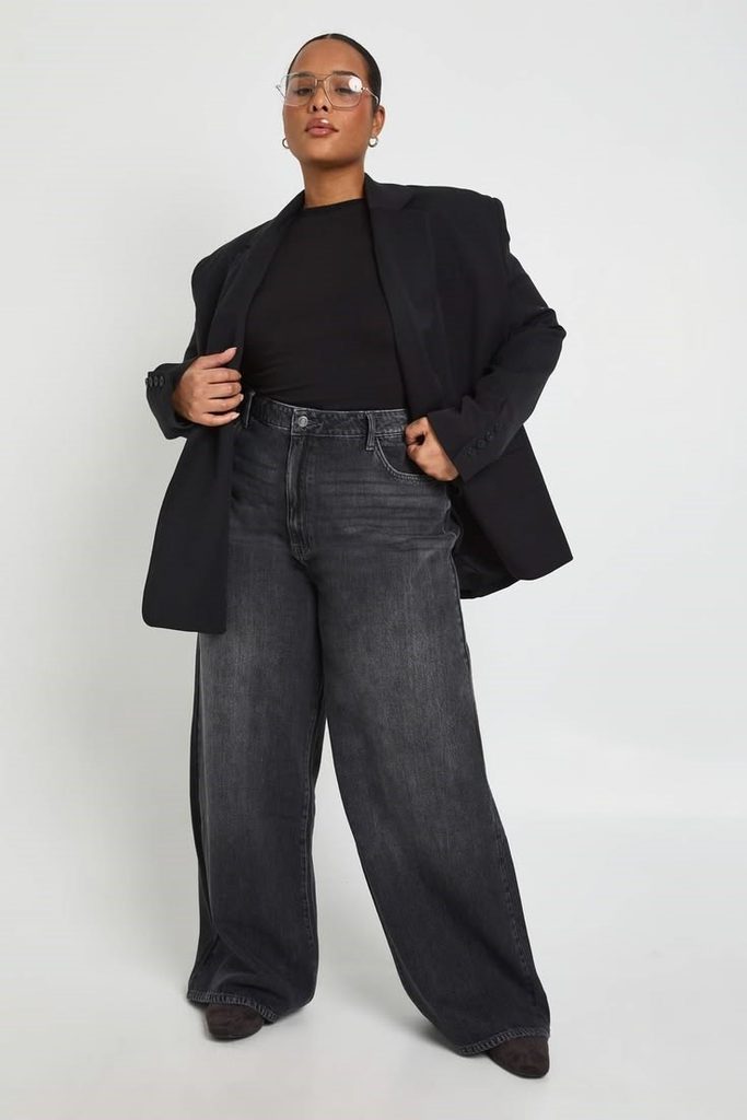 Plus size woman wearing black wide-leg jeans with a black top and oversized blazer