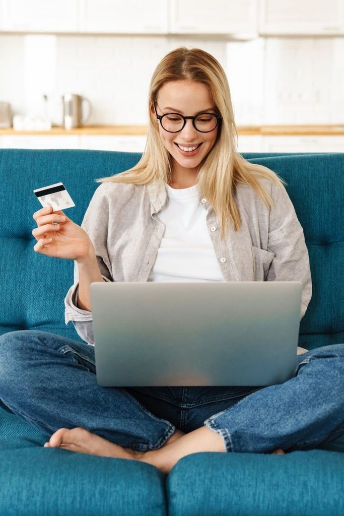 Woman shopping for clothes online with a laptop and credit card while avoiding online shopping mistakes plus size women make