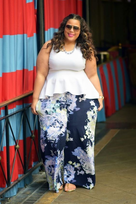 Plus size woman wearing a white peplum top with floral wide-leg pants for a baby shower