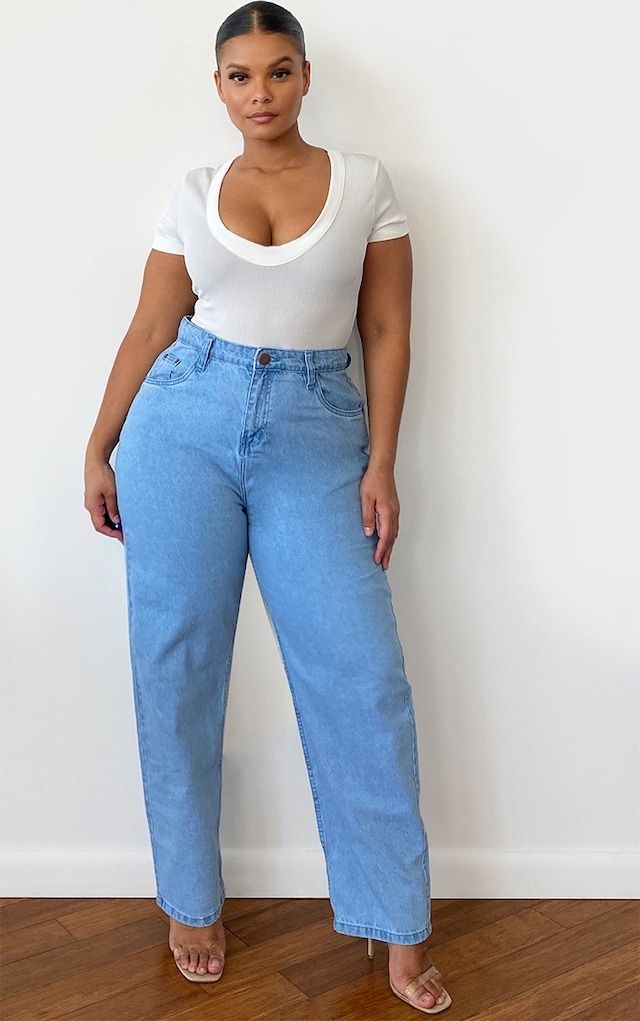 Plus size woman wearing light-wash straight-leg jeans with a fitted white top