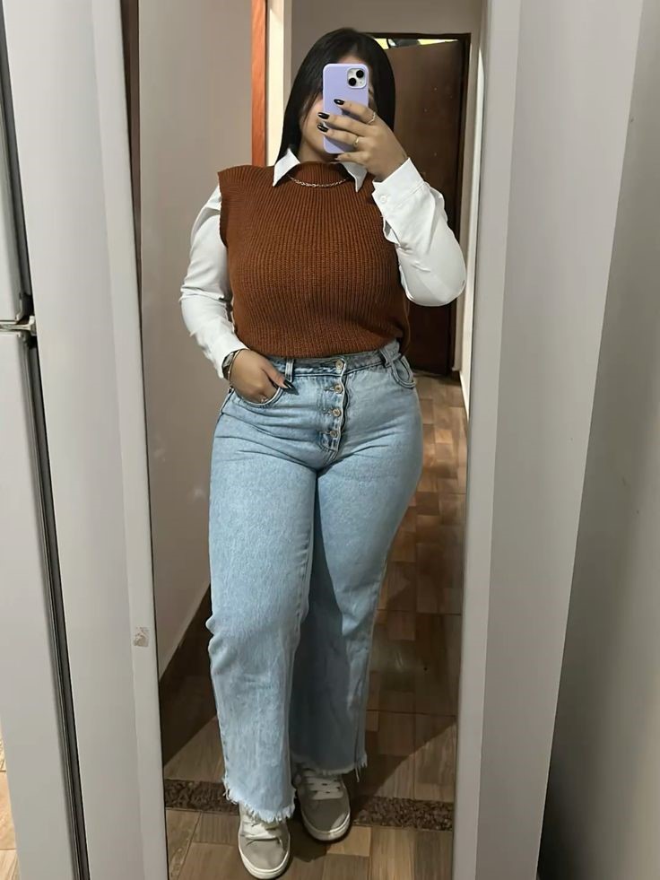 Plus size woman wearing straight-leg jeans with a sweater vest and white shirt