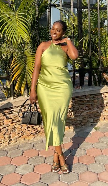 Woman wearing a green satin midi dress, showing the one dress style wedding guests always love for a summer wedding