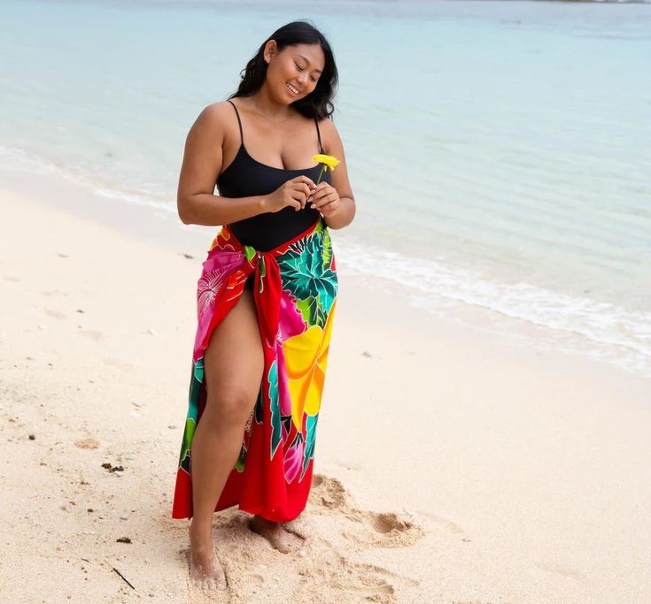 Beach Cover-Up Ideas You'll Wear All Vacation featuring a colorful floral sarong over a one-piece swimsuit