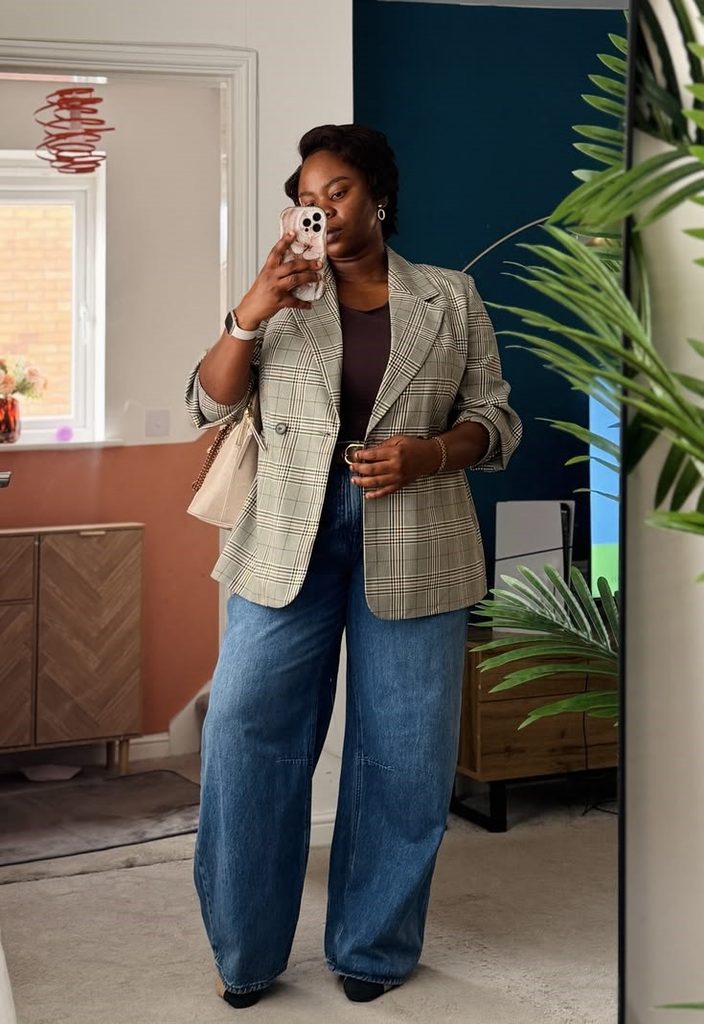 Cozy fall outfit for curvy women featuring a plaid blazer, dark top, and wide-leg blue jeans