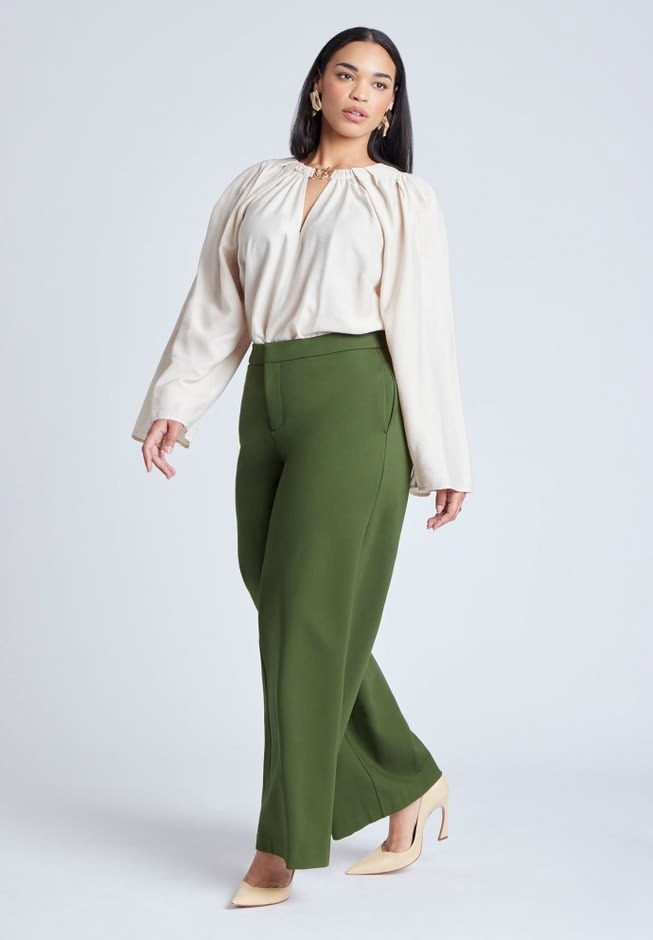 Woman wearing a cream blouse with olive-green wide-leg trousers and nude pointed-toe heels.